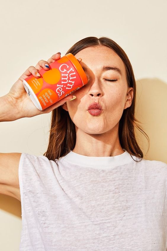 Model drinking from a Grummies supplement can against a soft neutral wall